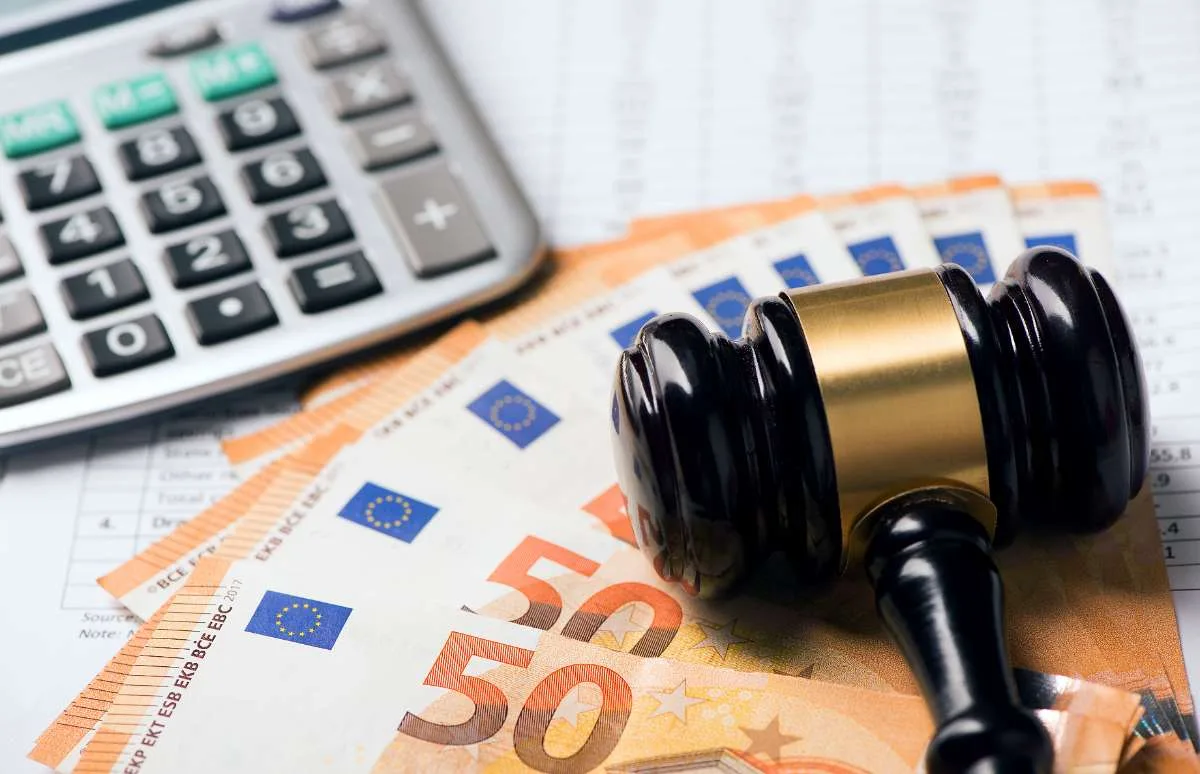 Martillo judicial sobre billetes de euro junto a una calculadora, simbolizando una reclamación económica.
