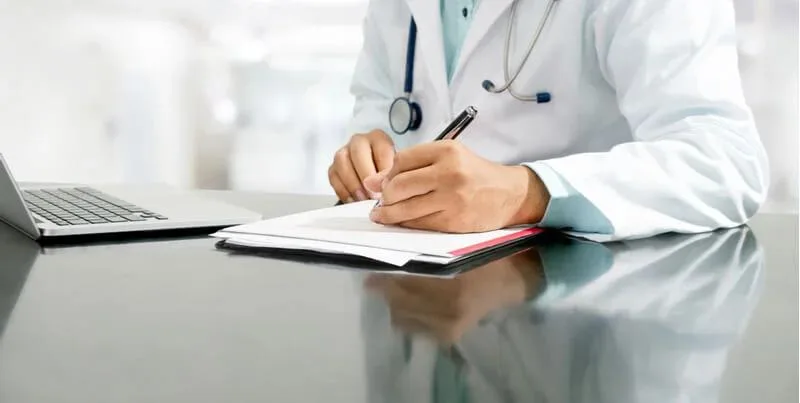 Perito médico elaborando un informe médico pericial para una reclamación de lesiones ante la aseguradora.